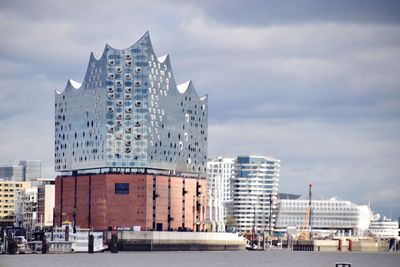 Modern buildings in city against cloudy sky