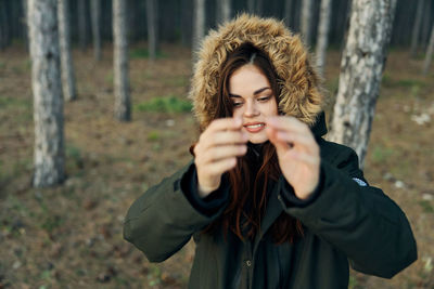 Portrait of young woman standing against tree