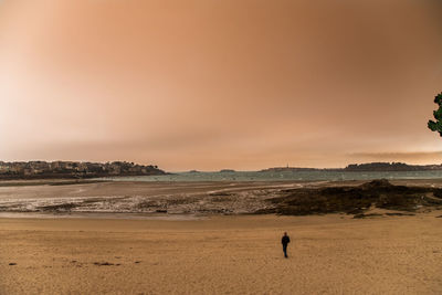 Man standing on beach against sky during sunset