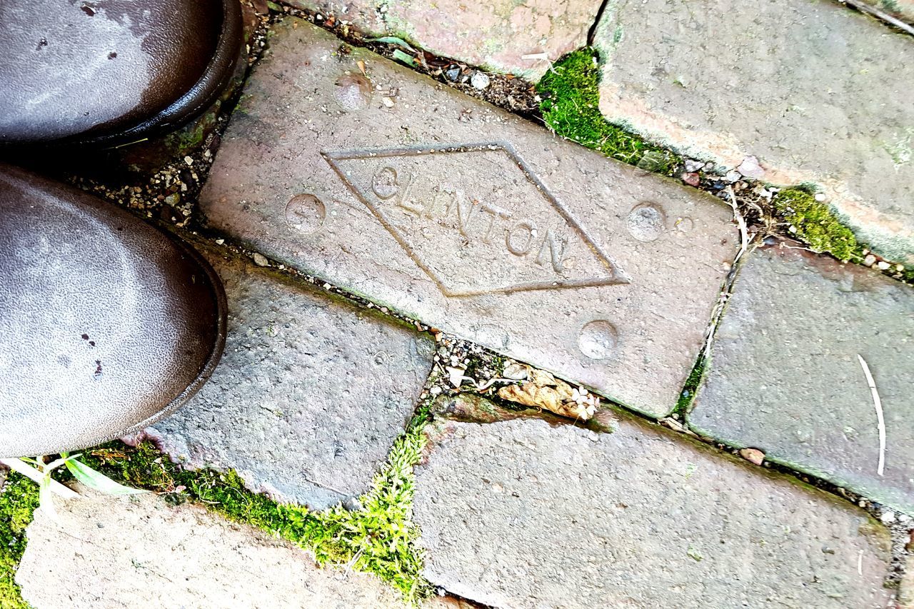 high angle view, paving stone, cobblestone, footpath, street, green color, grass, plant, day, pavement, no people, outdoors, textured, stone material, pattern, stone - object, sidewalk, growth, sunlight, walkway