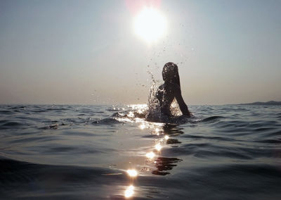 Silhouette woman swimming in sea against sky