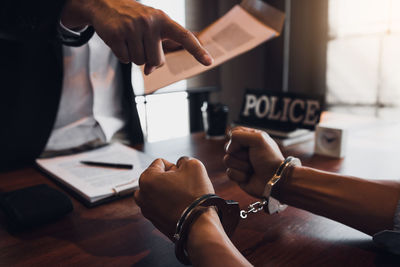 Midsection of woman holding hands on table