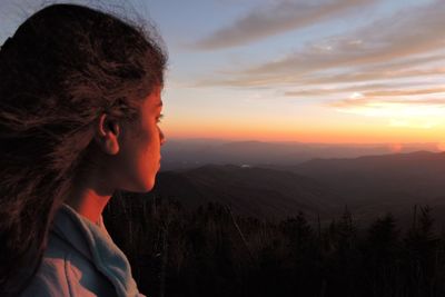 Side view of young woman looking at sunset