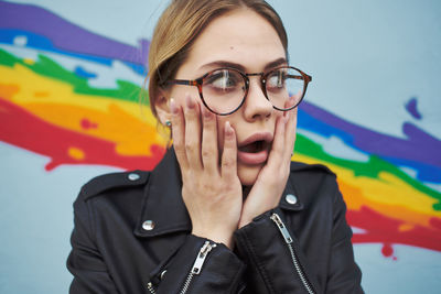 Surprised lesbian woman looking away against rainbow color