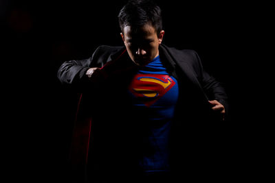 Portrait of man standing against black background