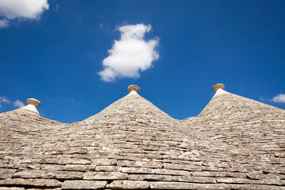 Low angle view of trulli houses against blue sky