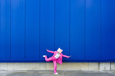 Full length of girl standing against blue wall