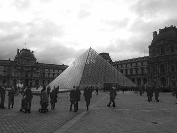 Tourists at town square against cloudy sky