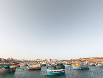 Boats moored in sea against clear sky