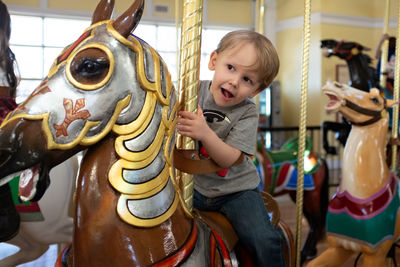 Cute boy on carousel in amusement park