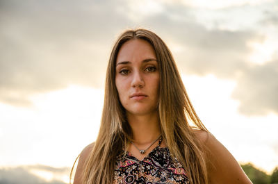 Portrait of young woman standing against sky