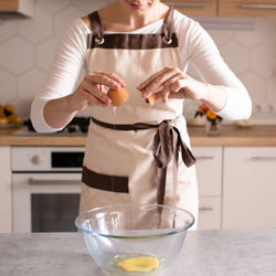 Midsection of woman pouring egg yolk in bowl