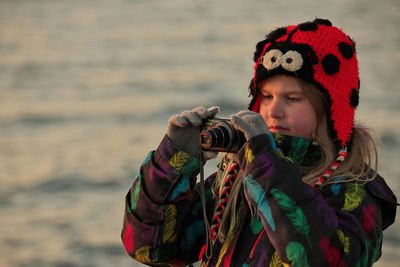 A 9 year old girl practices her photography and camera skills at the beach in the evening