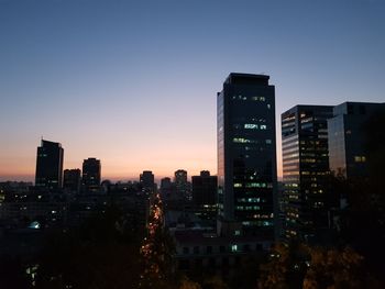 Illuminated buildings in city against sky during sunset