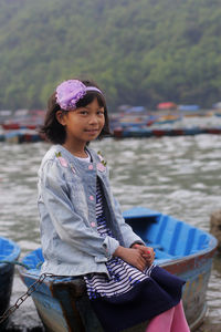 Portrait of smiling girl sitting on paddle boat at lakeshore
