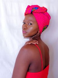 Portrait of woman with pink hair standing against white background