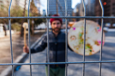 Portrait of man holding metal fence