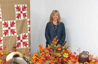 Portrait of smiling woman with flowers standing against wall