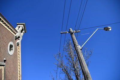 Low angle view of electricity pylon against clear blue sky