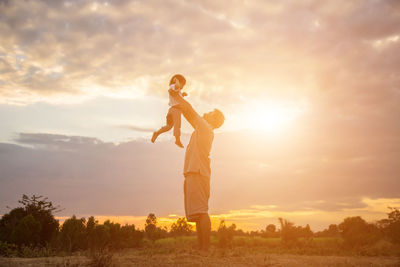 Man standing on field against sky during sunset