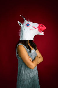 A woman in a unicorn mask on a red background with copy space.