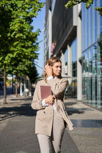 Portrait of young woman standing in city