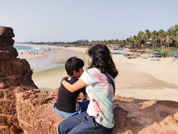 Rear view of couple on beach against sky