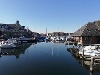 Sailboats moored at harbor against clear sky