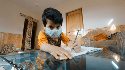 Portrait of boy sitting on table at home