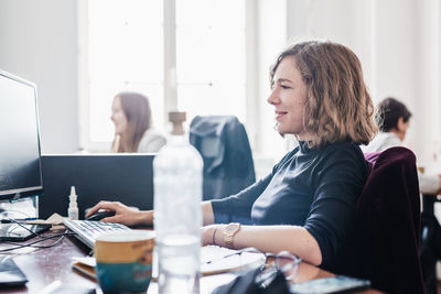 Side view of woman using laptop at home