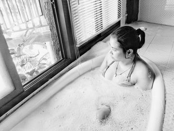 Thoughtful young woman in bathtub at home