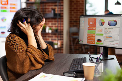 Side view of young woman using mobile phone in cafe