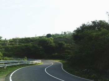 Road amidst trees against clear sky