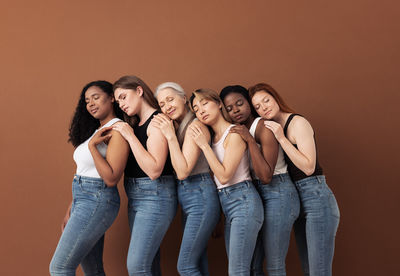 Women standing against brown background