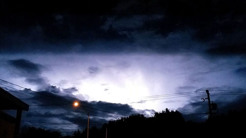 Low angle view of silhouette electricity pylon against sky