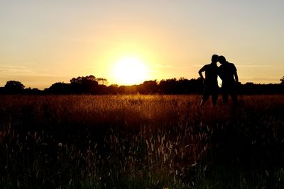 Silhouette man standing on field against sky during sunset