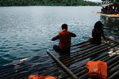 Rear view of people sitting on boat in river