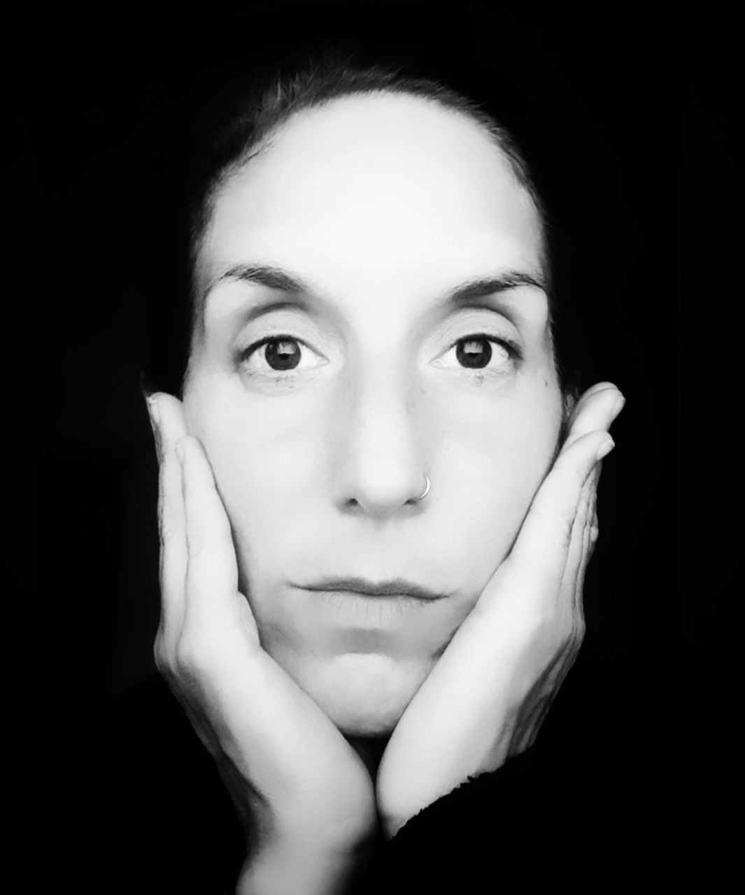 portrait, black and white, one person, looking at camera, black background, human face, studio shot, monochrome photography, women, young adult, headshot, adult, indoors, monochrome, human head, front view, portrait photography, close-up, white, hand, person, skin, black, female, nose, emotion, human eye, lifestyles