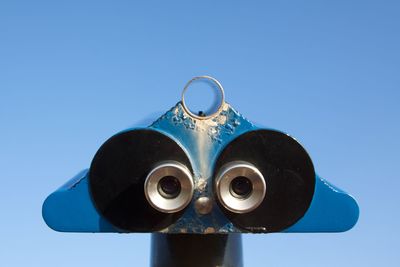 Low angle view of coin-operated binoculars against clear blue sky
