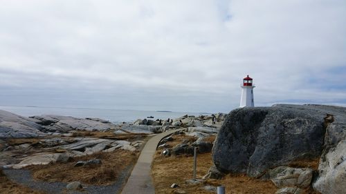 Scenic view of landscape by sea against cloudy sky