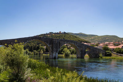 Arch bridge over river against clear sky