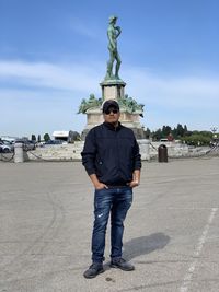 Portrait of man standing on land against statue and sky