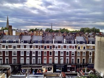 Buildings in city against cloudy sky