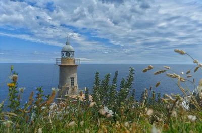 Lighthouse by sea against sky