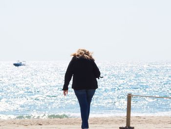 Rear view of woman standing at beach