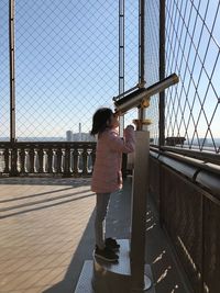 Rear view of woman standing on bridge against sky