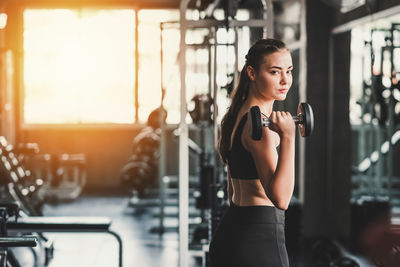 Portrait of young woman lifting dumbbell in gym