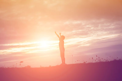 Silhouette woman standing against orange sky