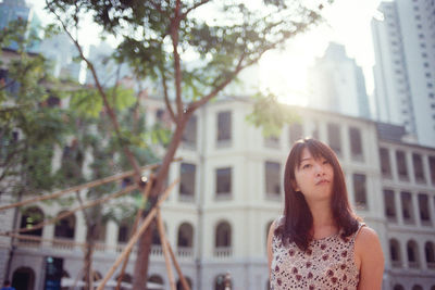 Portrait of woman standing by building in city