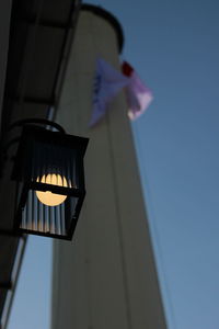 Low angle view of illuminated lamp against building